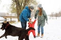 Full height of happy family with one naughty toddler and dog in winter casual oufit walking having fun outdoors