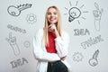 Full of ideas. Charming blonde woman in white shirt with hand on her chin looking at camera and smiling while standing