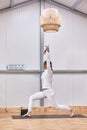 full image of attractive muscular young woman practicing hatha yoga at gym, standing barefooted on mat in Virabhadrasana 2 or