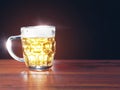 Full jar of lager beer with froth on a wooden table glowing in a dark. Alcohol consumption and sale. Copy space. Light flare Royalty Free Stock Photo