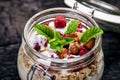 Full jar of muesli, yogurt, raspberries, nuts on a black, burnt wood table. Homemade breakfast cereals food. Healthy eating