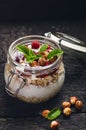 Full jar of muesli, yogurt, raspberries, nuts on a black, burnt wood table. Homemade breakfast cereals food. Healthy eating