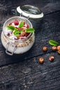 Full jar of muesli, yogurt, raspberries, nuts on a black, burnt wood table. Homemade breakfast cereals food. Healthy eating Royalty Free Stock Photo