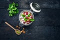 Full jar of muesli, yogurt, raspberries, nuts on a black, burnt wood table. Homemade breakfast cereals food. Healthy eating Royalty Free Stock Photo