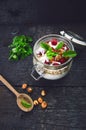 Full jar of muesli, yogurt, raspberries, nuts on a black, burnt wood table. Homemade breakfast cereals food. Healthy eating Royalty Free Stock Photo