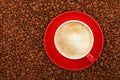 Full latte in red cup with saucer on coffee beans Royalty Free Stock Photo