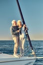 Full leghth of beautiful happy senior couple in love, retired man and woman standing on the side of sail boat floating