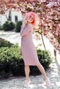 Full lengh photo of pretty young woman with curly pink hair and sunglasses near the blossoming spring tree. Royalty Free Stock Photo