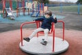 Full lengh portrait active school kid playing in park, Happy boy sitting on merry go round in playground, Child having fun outdoor