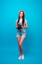 Full-lengh portrait of cheerful young woman using camera for taking photos