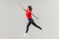 Full lenght of happy beautiful brunette young woman in casual red shirt jumping up in super hero pose and looking forward with Royalty Free Stock Photo