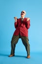 Full lenght image. Balded man with mustache dressed vintage dansing with call-sign and shouting over blue background.