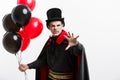 Full-lenght Portrait of handsome caucasian Vampire in black and red halloween costume.