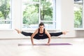Full lenght portrait of young adult gumnastics beautiful woman in black pants and top is doing hand stand split, practicing yoga Royalty Free Stock Photo