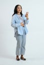 full lenght shoot of asian indonesian woman holding smartphone with hungry gesture on isolated background