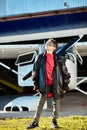 Full lenght shot of little boy in large father`s leather pilot jacket