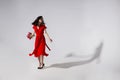 Full lengt view of a brunette young woman in long flying red dress holding a bouquet of tulips and spins. Royalty Free Stock Photo