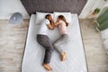 Full length of affectionate multiracial couple sleeping together on bed, facing each other, top view