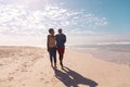 Full length of african american couple walking on sandy beach against cloudy sky on sunny day Royalty Free Stock Photo