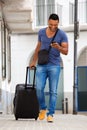 Full length african man walking with suitcase and using mobile phone Royalty Free Stock Photo