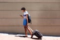 Full length african woman walking outdoors with suitcase and cell phone Royalty Free Stock Photo