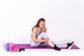 Full length athletic woman in white sportswear sitting on gym mat touching injured caviar, suffering calf muscle strain after yoga Royalty Free Stock Photo