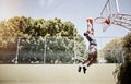 Full length of basketball player dunking a ball into the net during a match on a court. Fit and active athlete jumping Royalty Free Stock Photo