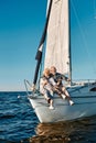 Full length of a beautiful and happy senior family couple embracing and smiling at camera while relaxing on a sail boat Royalty Free Stock Photo