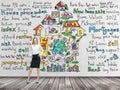 Full length beautiful woman in formal clothes with hands on the waist. Colourful ' home sales ' icons are drawn on the concrete wa