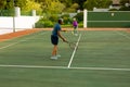 Full length of biracial senior man serving ball to senior woman while playing tennis in court Royalty Free Stock Photo
