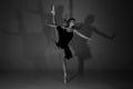 Full length black and white photo of beautiful young blonde ballet dancer in a black dress and pointes in complex pose