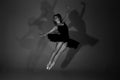 Full length black and white photo of beautiful young blonde ballet dancer in a black dress and pointes in complex pose Royalty Free Stock Photo