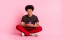 Full length body photo of positive student guy sitting using cellphone addiction texting message isolated on pink color Royalty Free Stock Photo