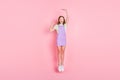 Full length body size photo of amazed small girl jumping high showing little big size isolated pastel pink color