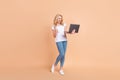Full length body size photo blonde woman gesturing like winner keeping laptop isolated pastel beige color background Royalty Free Stock Photo