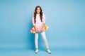 Full length body size photo of cheerful positive pink schoolchild holding skateboard smiling cheerfully isolated pastel