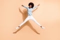 Full length body size photo of curly funny girl with dark skin jumping pretending star isolated on beige color