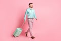Full length body size photo of happy man with suitcase going to terminal in airport smiling isolated on pastel pink Royalty Free Stock Photo