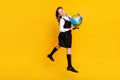 Full length body size photo little schoolgirl jumping up keeping globe isolated vivid yellow color background