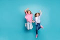 Full length body size photo of two rejoicing encouraged excited free girls jumping while isolated with blue background