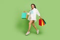 Full length body size photo woman keeping bags jumping running on sale isolated pastel green color background Royalty Free Stock Photo