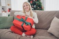 Full length body size photo woman in white pullover keeping big present box sitting on sofa at home Royalty Free Stock Photo