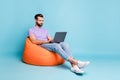Full length body size photo of young entrepreneur working with laptop in beanbag isolated on bright blue color