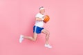 Full length body size side profile photo senior man jumping up playing basketball throwing ball isolated pastel pink Royalty Free Stock Photo