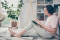 Full length body size side profile photo senior woman sitting on floor in casual clothes reading book spending free time