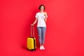 Full length body size view of attractive cheerful girl using device carrying bag departure taxi isolated over bright red