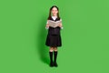 Full length body size view of attractive cheerful schoolgirl reading book isolated over bright green color background Royalty Free Stock Photo