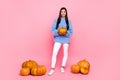 Full length body size view of attractive cheery girl holding fresh pumpkins sale isolated over pink pastel color