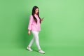 Full length body size view of attractive focused cheerful girl going using device chatting isolated over green pastel
