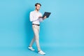 Full length body size view of attractive man going using laptop isolated over bright blue color background